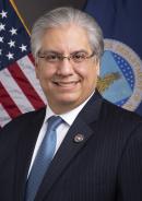 Smiling man standing in front of an American flag and the USDA flag; Maximiliano Trujillo, State Director for Puerto Rico 