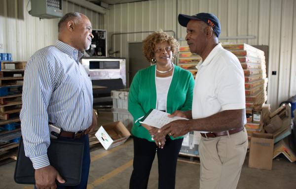 State Director Perry Hickman and Area Director Laurette Tucker confer with Brick Goldman (right) in the cooperative's original aggregation facility.