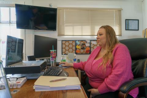 Mary West-Hutchison, a real estate broker in West Point, California, sits at a computer in her office. Papers and other office content rest on her desk.