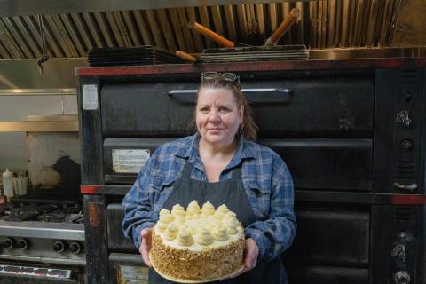 Woman standing in kitchen holding a white cake