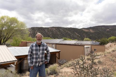 Man standing on trail with solar panels and mountains in background