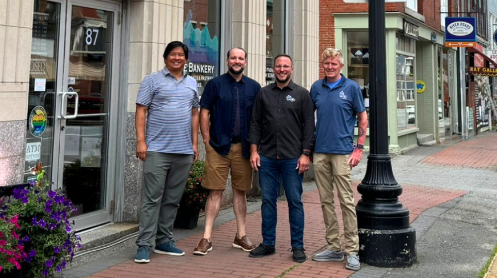 Brian Eng of Sustaine and the three owners of The Bankery and Skowhegan Fleuriste stand on the sidewalk in front of The Bankery with other businesses visible in the background. 