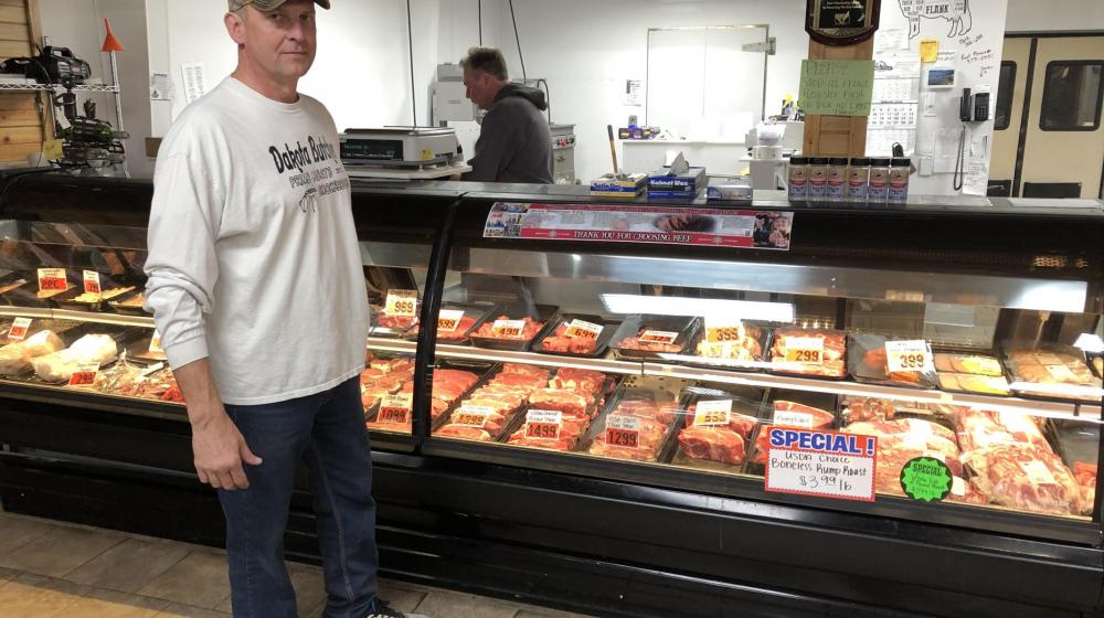 Randy Gruenwald standing in front of a display of meats.