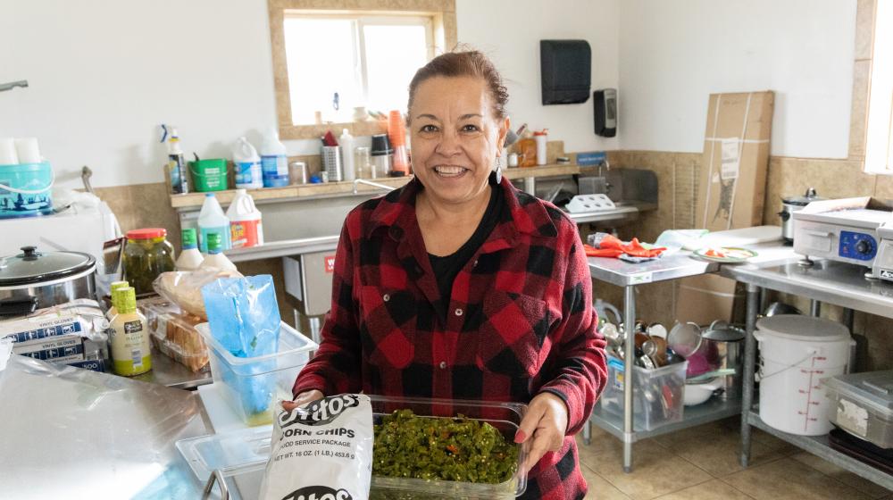 Woman holding green chile in her restaurant kitchen