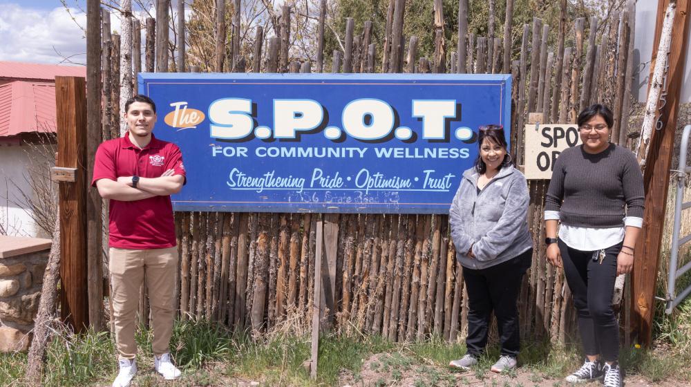 Three people standing next to a sign that say S.P.O.T.