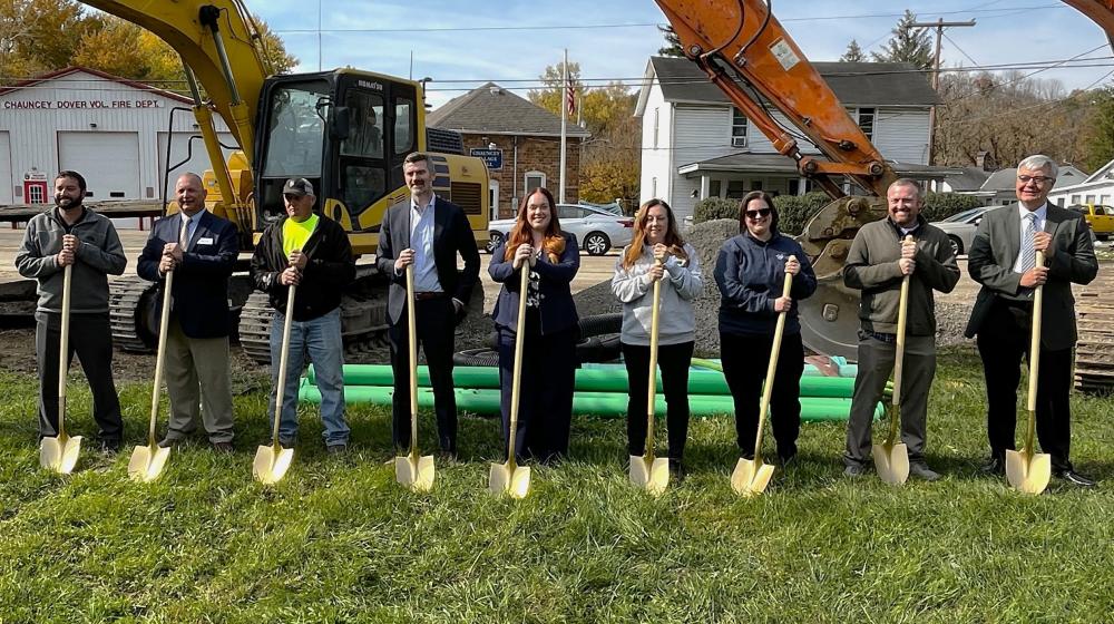 People with shovels in front of large machinery