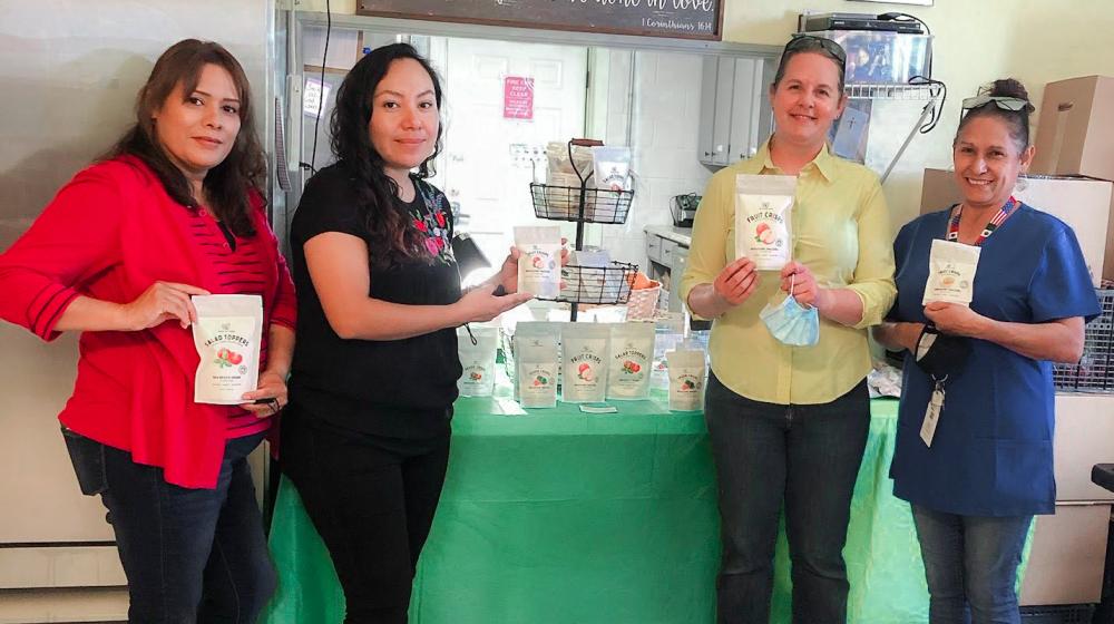 Staff from Back Yard Farms hold packages of apple chips that were just produced and ready for sale using the freeze-drying method. 