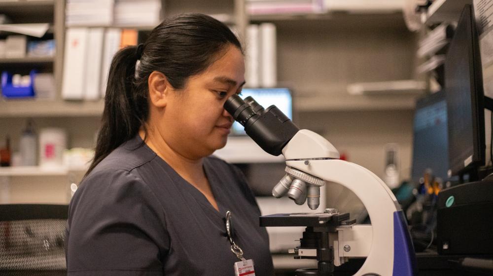 Lab Technician at Exceptional Hospital Bullhead City Looks Into Microscope.