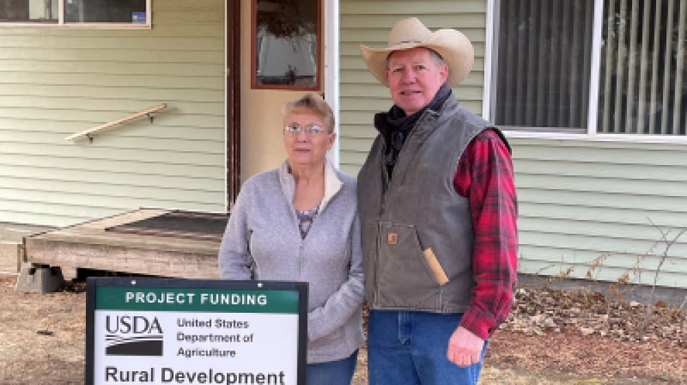 Woman and man standing in front of their home in Montana.