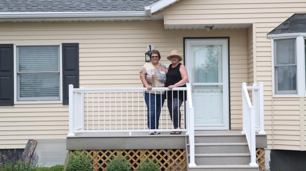Melanie Bauer Dukart and DIane Wiege pose in front of her home in Hazen, North Dakota.