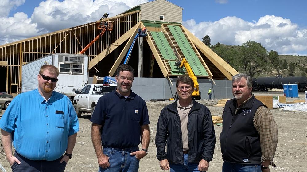 Four men stand in front of a fertilizer production plant under construction in Montana.