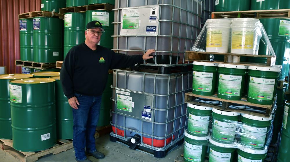 Renewable Lubricants CEO Bill Garmier stands in front of barrels of Lubricant Products