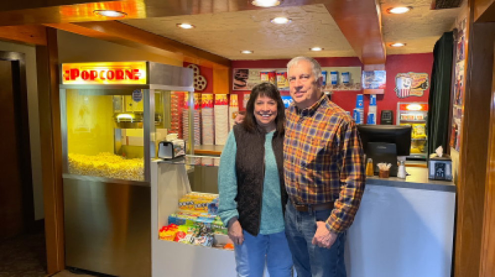 Woman and man standing in front of concession stand at movie theater.