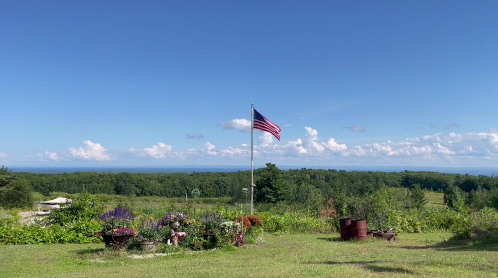 View of blue skies and Lake Superior with American flag in the middle.