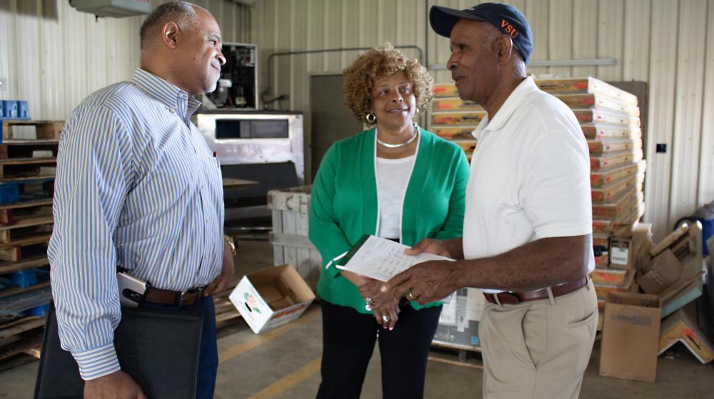 State Director Perry Hickman and Area Director Laurette Tucker confer with Brick Goldman (right) in the cooperative's original aggregation facility.