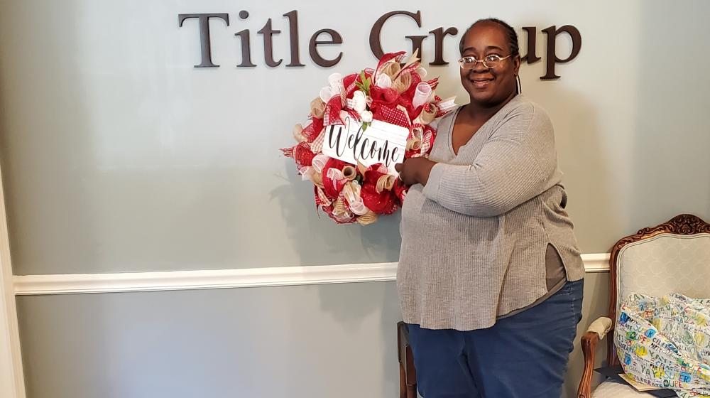 Smiling woman, Latanya Moultry, holding a wreath after closing on her new home.