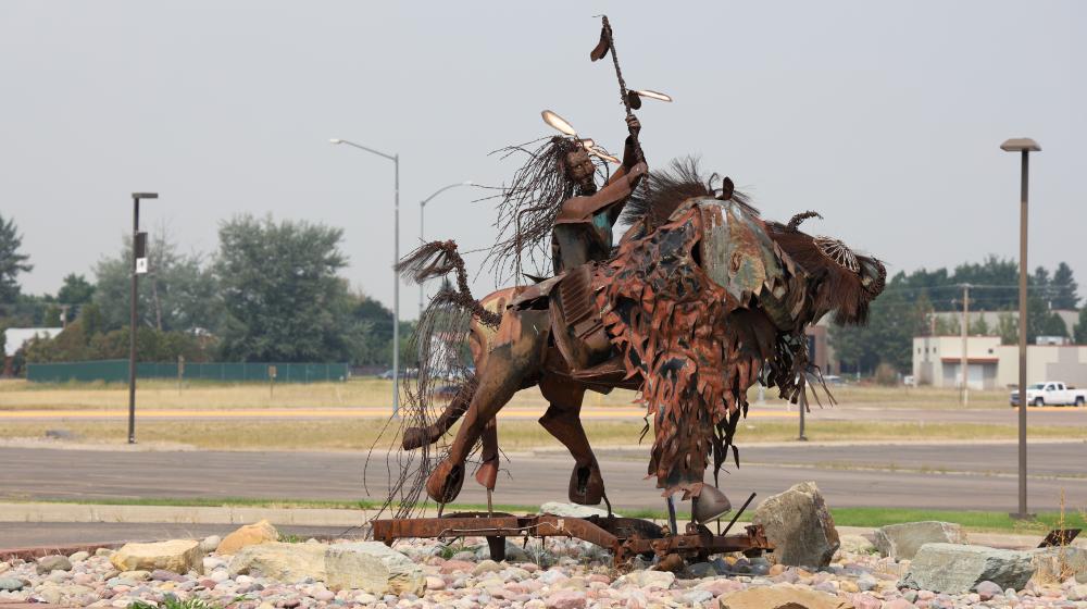 Metal sculpture with parking lot in back 