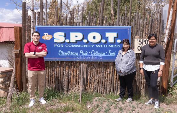 Three people standing next to a sign that say S.P.O.T.