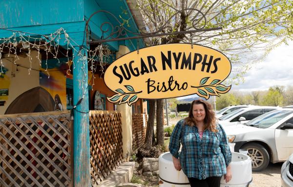 Woman standing under Sugar Nymphs Bistro sign next to parking lot