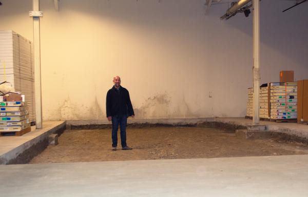 Richard Berkfield of Food Connects stands in a large, shallow square hollow in a cement floor