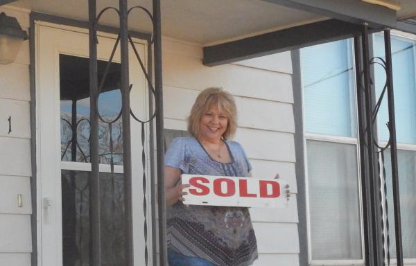 Cindy proudly holds the SOLD sign.