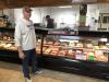 Randy Gruenwald standing in front of a display of meats.