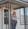 Cindy proudly holds the SOLD sign.